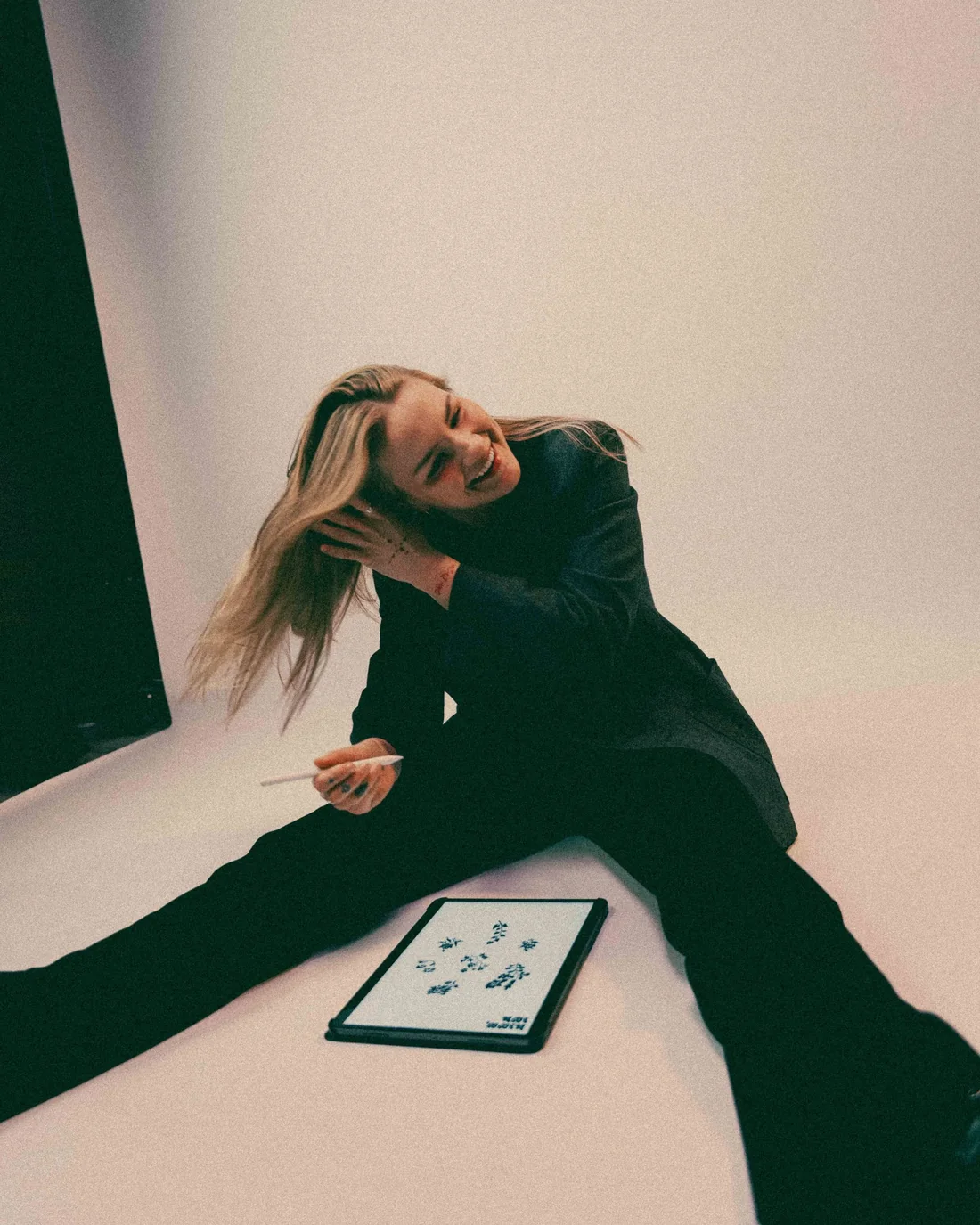 Hilda van HiKu lacht, zittend op de grond met haar iPad en tekenpen